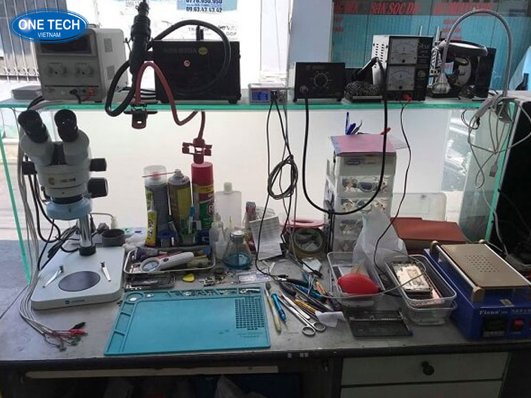 Thợ sửa chữa điện thoại đang kiểm tra linh kiện trong cửa hàng sửa chữa điện tử nhỏ ở nông thôn