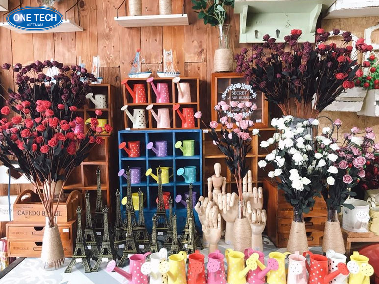 Người phụ nữ đang bày bán các sản phẩm handmade tại nhà trong hẻm, gồm túi vải, đồ len và tranh thêu tay
